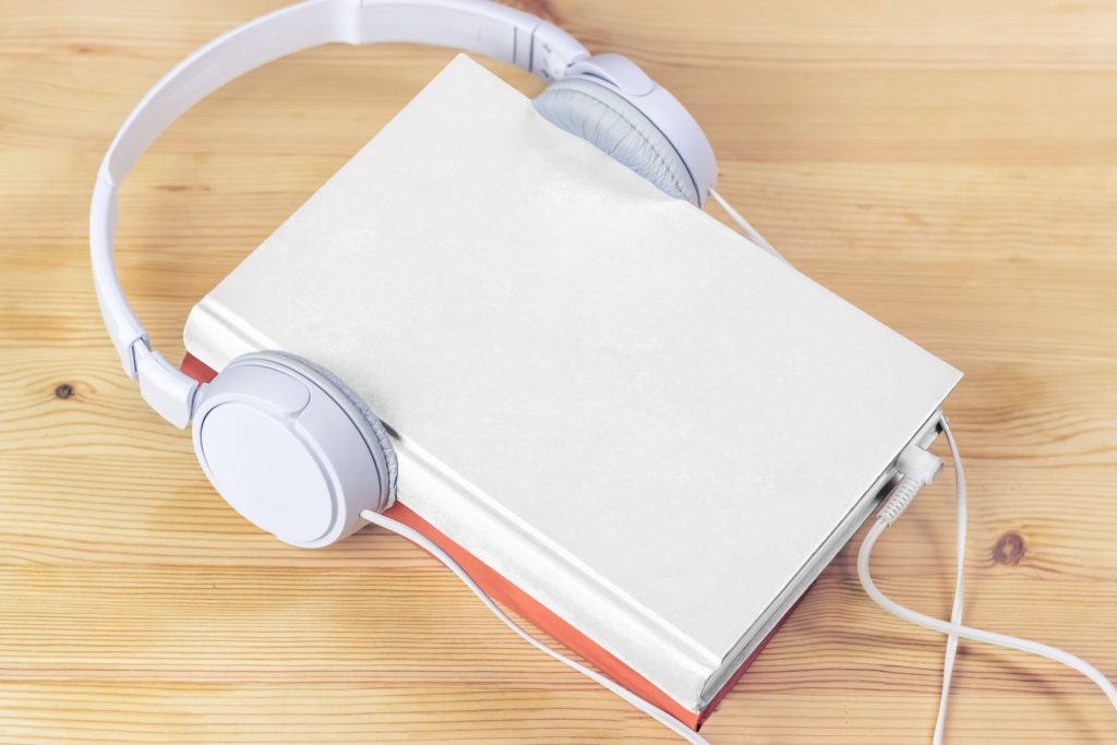 Hardcover book big headphones on wood background.