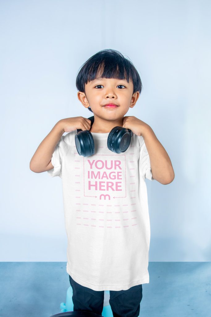 cute boy with t shirt. big headphones are on. wearing black pants. standing on a light background