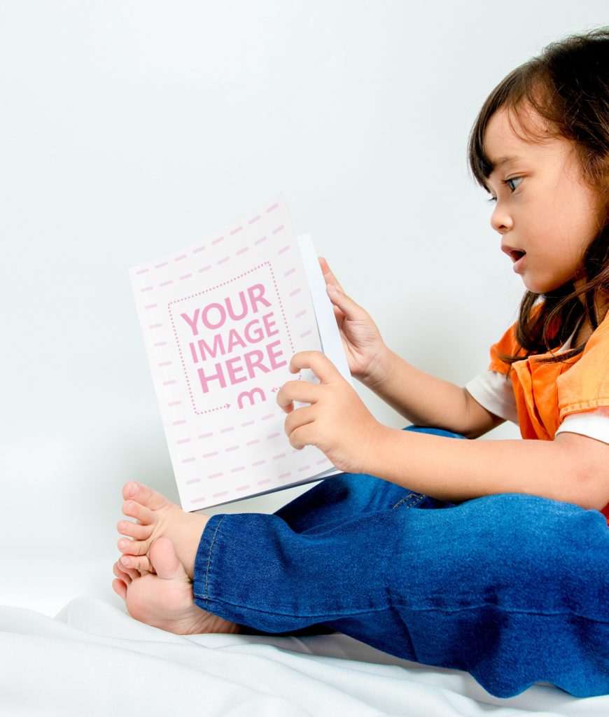 A little girl is sitting and reading a book.