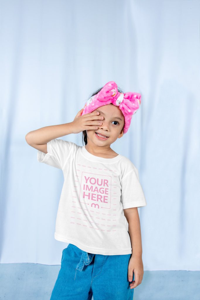 the girl is rubbing her eyes. she is sleepy. she has a scarf on her head and is wearing a t-shirt