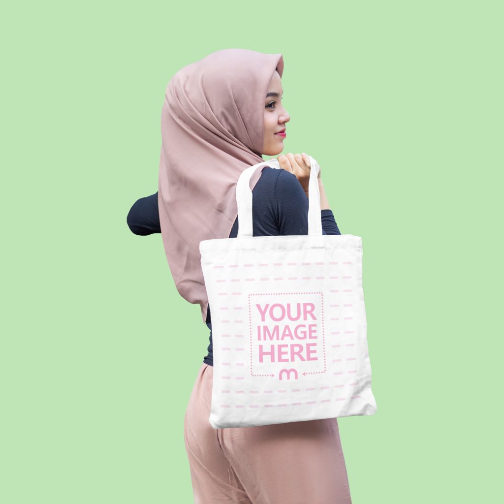 Muslim woman poses with tote bag in studio. He has a Tote Bag on his back. The woman is smiling and confident.
