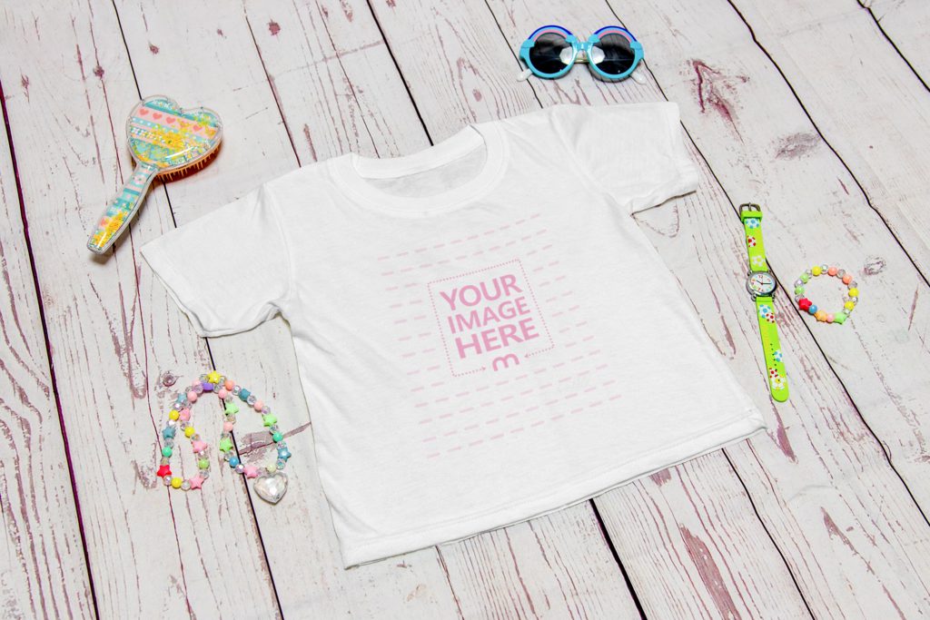 t-shirt on a wooden background. next to the shirt is a watch, a necklace, a comb and a bracelet.
