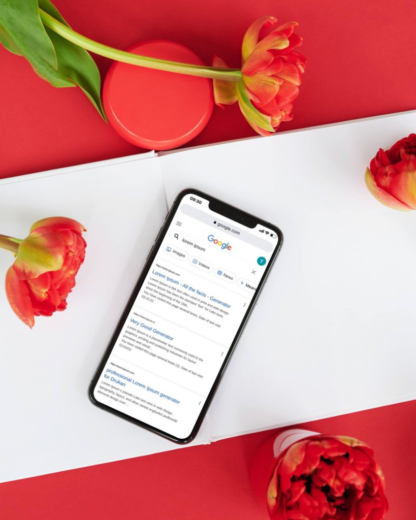 iphone with Google search mockup on the screen next to decorated desk and flowers